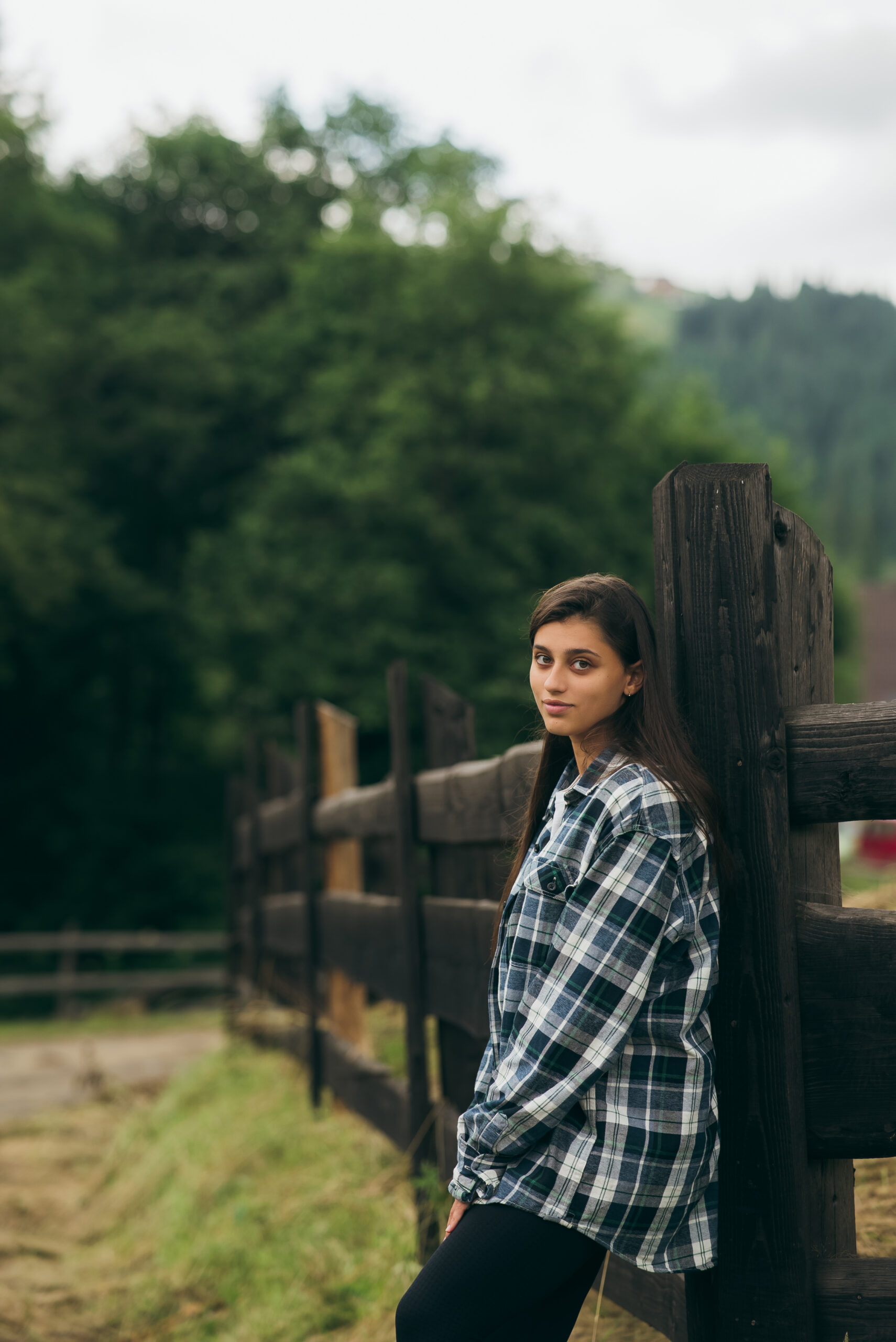 a young attractive caucasian female stand by a fence